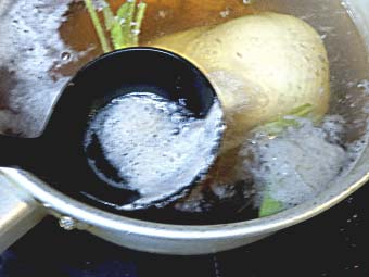カオマンガイ用の茹で鶏のアクを取る